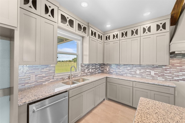 kitchen with tasteful backsplash, light stone countertops, sink, and stainless steel dishwasher