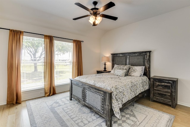 bedroom featuring ceiling fan, light hardwood / wood-style flooring, and vaulted ceiling