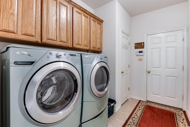 clothes washing area featuring light tile patterned floors, cabinets, and independent washer and dryer