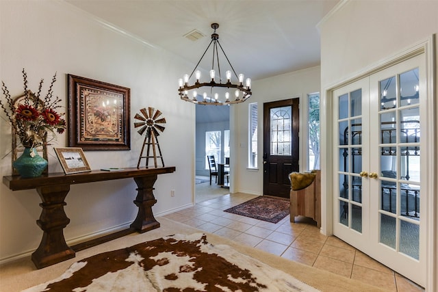 tiled foyer entrance featuring french doors, crown molding, and a notable chandelier