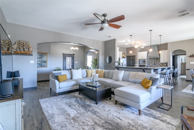 living room with ceiling fan with notable chandelier and dark hardwood / wood-style floors