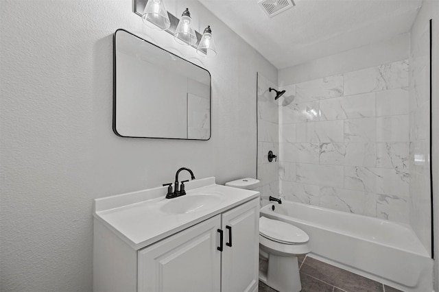 full bathroom featuring tile patterned floors, a textured ceiling, toilet, vanity, and tiled shower / bath