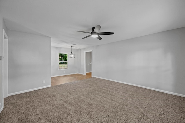 carpeted empty room featuring ceiling fan with notable chandelier