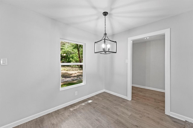 unfurnished dining area with a chandelier and hardwood / wood-style flooring