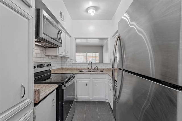 kitchen featuring backsplash, sink, light stone counters, white cabinetry, and stainless steel appliances