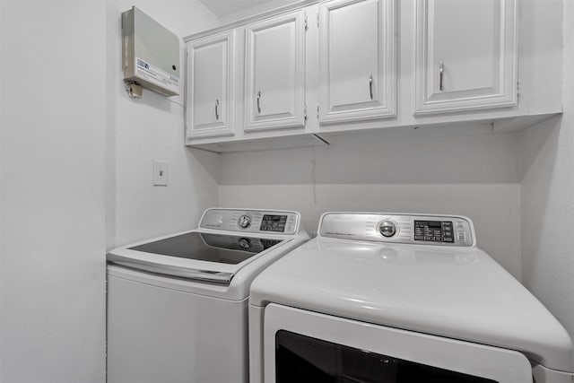 clothes washing area with cabinets and washing machine and dryer