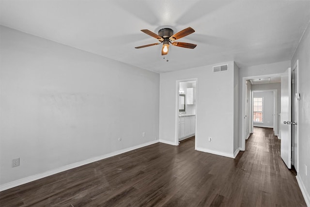 interior space featuring baseboards, visible vents, attic access, ceiling fan, and dark wood-type flooring