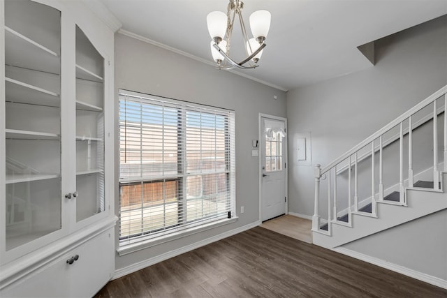 entryway with dark hardwood / wood-style floors, ornamental molding, and an inviting chandelier