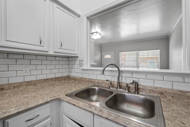 kitchen featuring white cabinets, decorative backsplash, ornamental molding, and sink