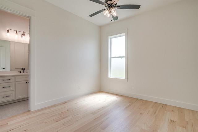 unfurnished bedroom featuring ensuite bath, light wood-type flooring, sink, and ceiling fan