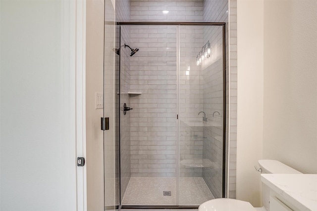 bathroom featuring vanity, toilet, and a shower with shower door