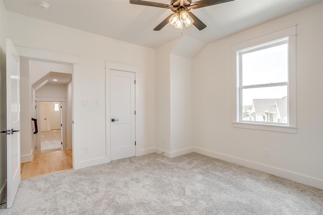 unfurnished bedroom featuring a closet, ceiling fan, lofted ceiling, and light colored carpet