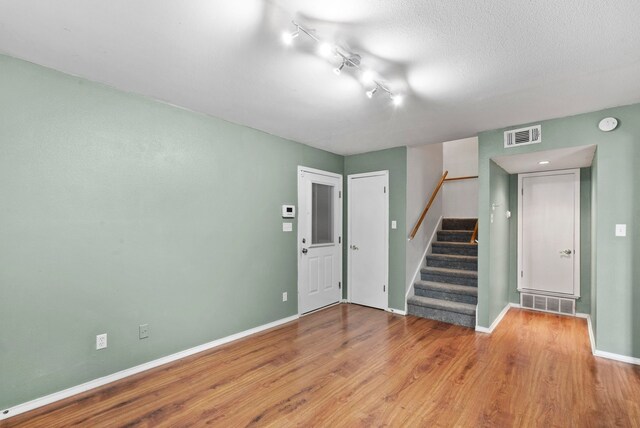 interior space featuring light hardwood / wood-style flooring, rail lighting, and a textured ceiling