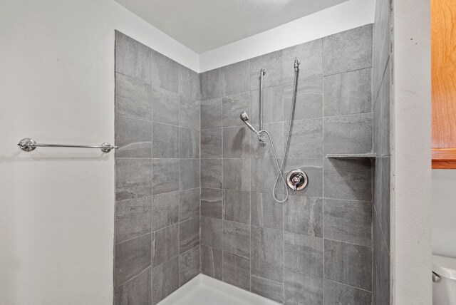 bathroom with toilet and a tile shower