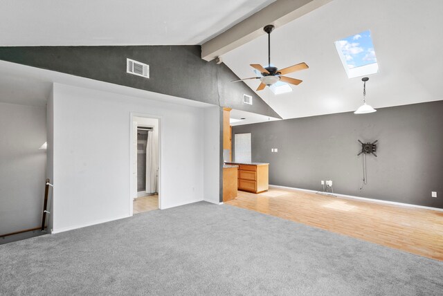 unfurnished living room with a skylight, ceiling fan, beamed ceiling, high vaulted ceiling, and light carpet