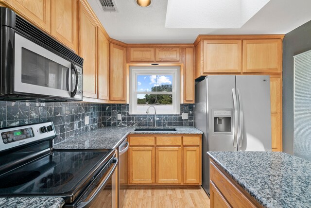 kitchen with decorative backsplash, stainless steel appliances, sink, light hardwood / wood-style flooring, and stone counters