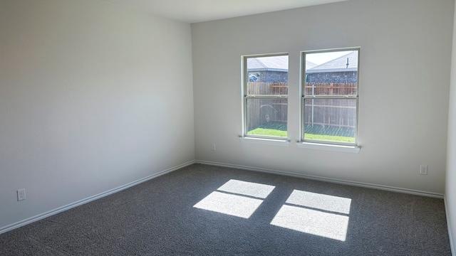 unfurnished room featuring dark carpet and plenty of natural light