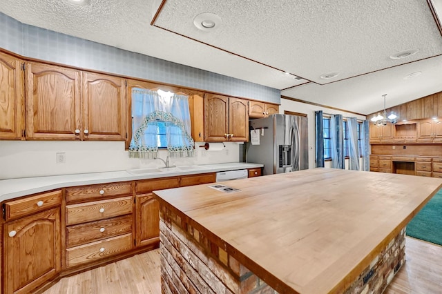 kitchen featuring stainless steel fridge, wooden counters, a notable chandelier, pendant lighting, and sink