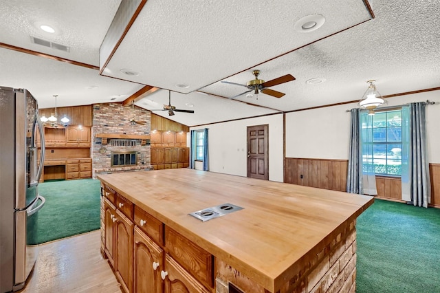 kitchen featuring hanging light fixtures, stainless steel fridge, wood counters, and a center island