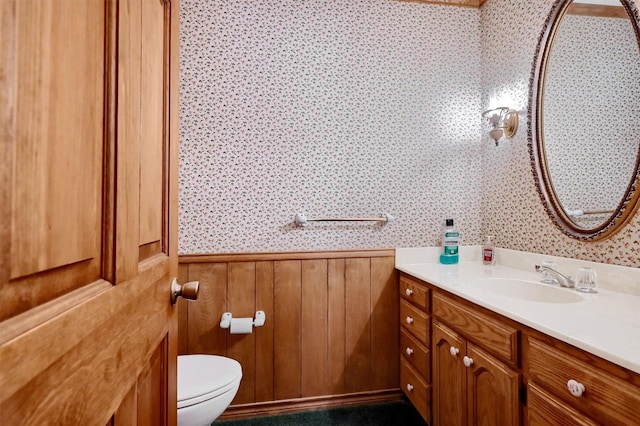 bathroom featuring toilet, vanity, and wooden walls