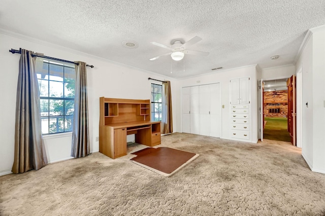 unfurnished living room with ceiling fan, light colored carpet, a textured ceiling, and crown molding