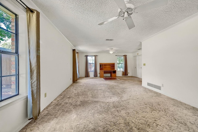 unfurnished living room with ceiling fan, a textured ceiling, ornamental molding, and carpet flooring