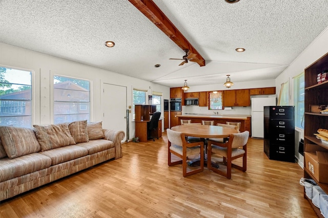 dining space with light hardwood / wood-style floors, a textured ceiling, lofted ceiling with beams, and ceiling fan