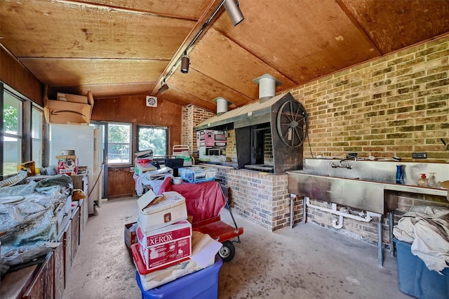 misc room with a fireplace, brick wall, lofted ceiling, and track lighting