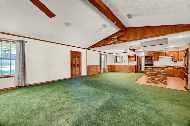 unfurnished living room featuring a textured ceiling, ceiling fan, light colored carpet, and lofted ceiling with beams