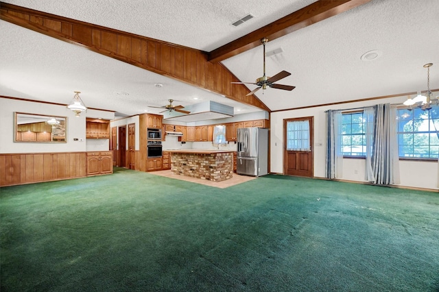 unfurnished living room with wood walls, carpet floors, a textured ceiling, ornamental molding, and lofted ceiling with beams