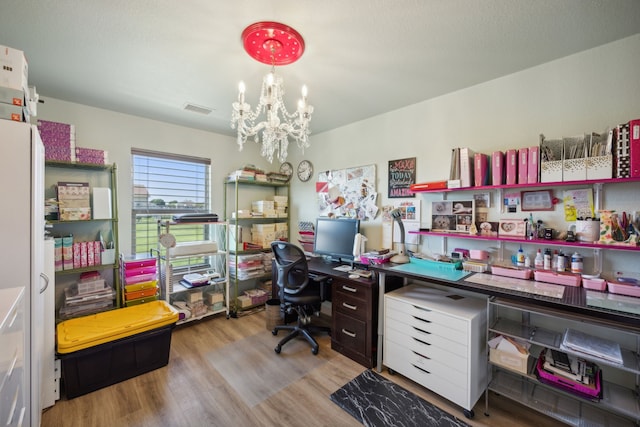 home office with light hardwood / wood-style floors and a chandelier