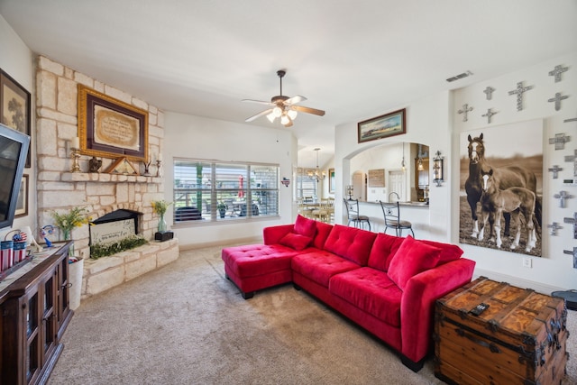 carpeted living room featuring a fireplace and ceiling fan with notable chandelier