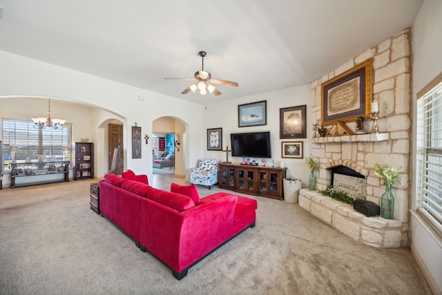 living room with a fireplace, ceiling fan with notable chandelier, and carpet