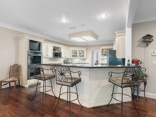 kitchen with stainless steel appliances, kitchen peninsula, dark wood-type flooring, and a kitchen breakfast bar