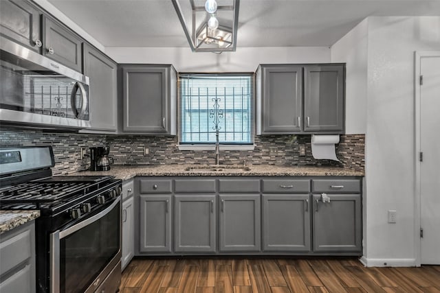 kitchen featuring stainless steel appliances, gray cabinetry, and light stone counters