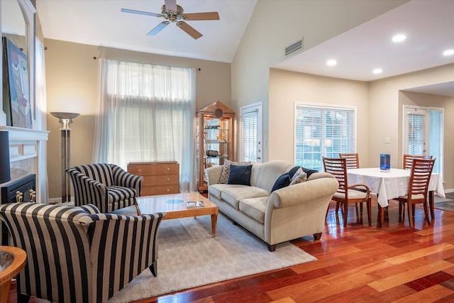 living room featuring ceiling fan, high vaulted ceiling, and light hardwood / wood-style flooring