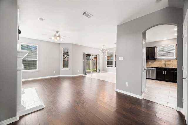 unfurnished living room featuring ceiling fan with notable chandelier, light wood-type flooring, and sink