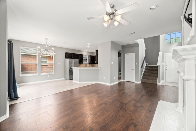 unfurnished living room featuring plenty of natural light, wood-type flooring, and ceiling fan with notable chandelier