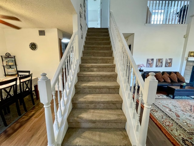 staircase featuring a textured ceiling and hardwood / wood-style flooring