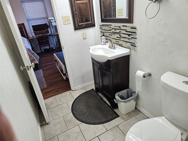 bathroom with toilet, decorative backsplash, vanity, and tile patterned floors