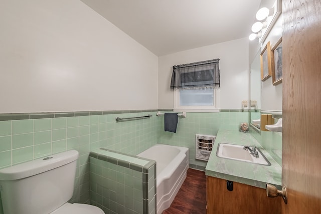 bathroom featuring a tub, vanity, hardwood / wood-style flooring, tile walls, and toilet