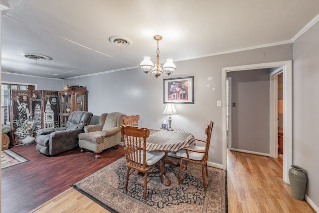 dining space with light wood-type flooring, crown molding, and a chandelier