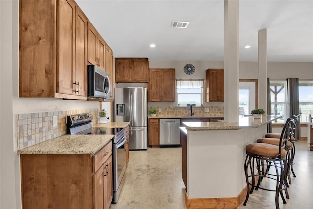 kitchen featuring appliances with stainless steel finishes, a breakfast bar area, visible vents, and decorative backsplash