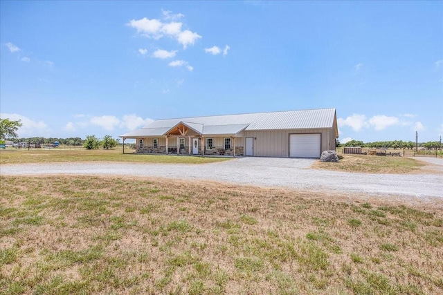 ranch-style house with a garage, metal roof, a front lawn, and gravel driveway