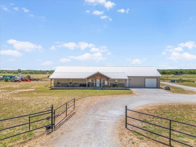 farmhouse inspired home featuring gravel driveway, a garage, metal roof, and a rural view