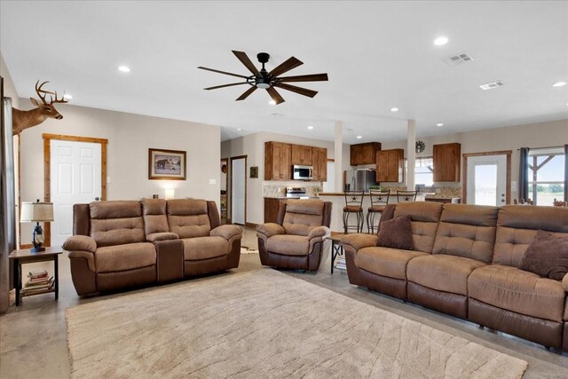 living room with finished concrete flooring, visible vents, and recessed lighting