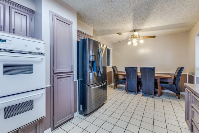 kitchen featuring visible vents, ceiling fan, fridge with ice dispenser, a textured ceiling, and double oven