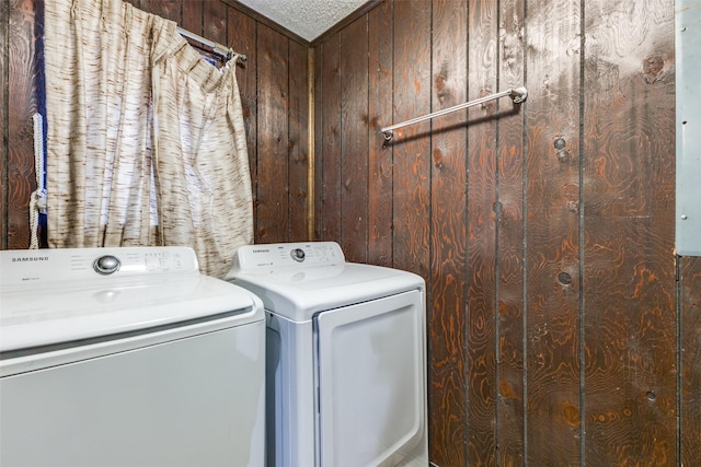 laundry area with laundry area, wood walls, and washer and clothes dryer