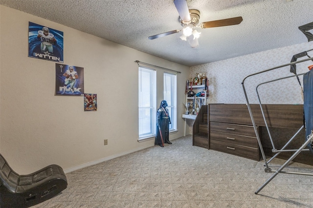 carpeted bedroom featuring a textured ceiling, wallpapered walls, a ceiling fan, and baseboards