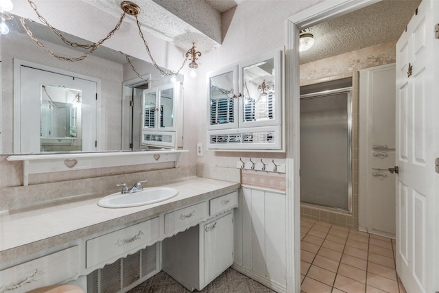 full bathroom with a stall shower, a textured ceiling, vanity, and tile patterned floors